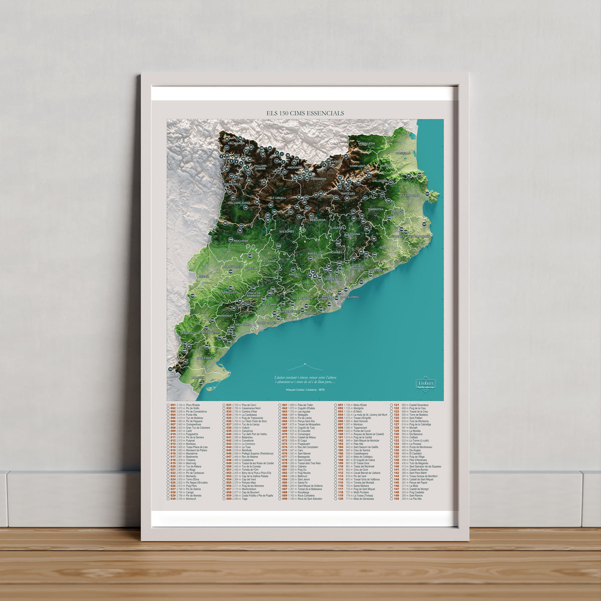 Mapa de las 150 cimas esenciales, colores clásicos, 30 × 40 cm. Lámina en un marco claro apoyado sobre madera. Marco no incluido.