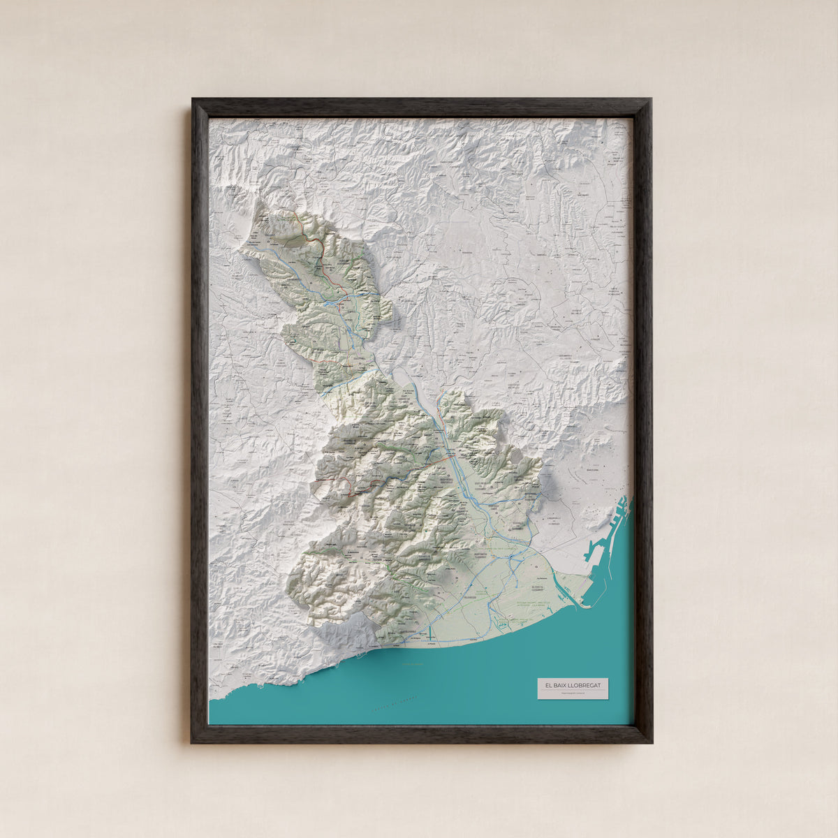 Mapa de relleu del Baix Llobregat, amb el territori en color i l’entorn en blanc. Presentació amb marc. 70 × 100 cm. Estil Cartogràfic.