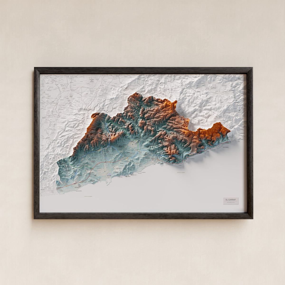 Mapa de relleu del Garraf, amb el territori en color i l’entorn en blanc. Presentació amb marc. 61 × 91 cm. Estil Blau i taronja.