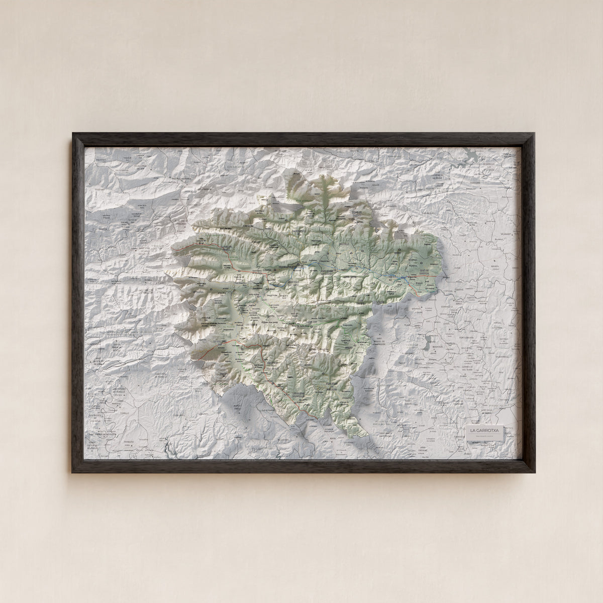 Mapa de relleu de la Garrotxa, amb el territori en color i l’entorn en blanc. Presentació amb marc. 50 × 70 cm. Estil Cartogràfic.