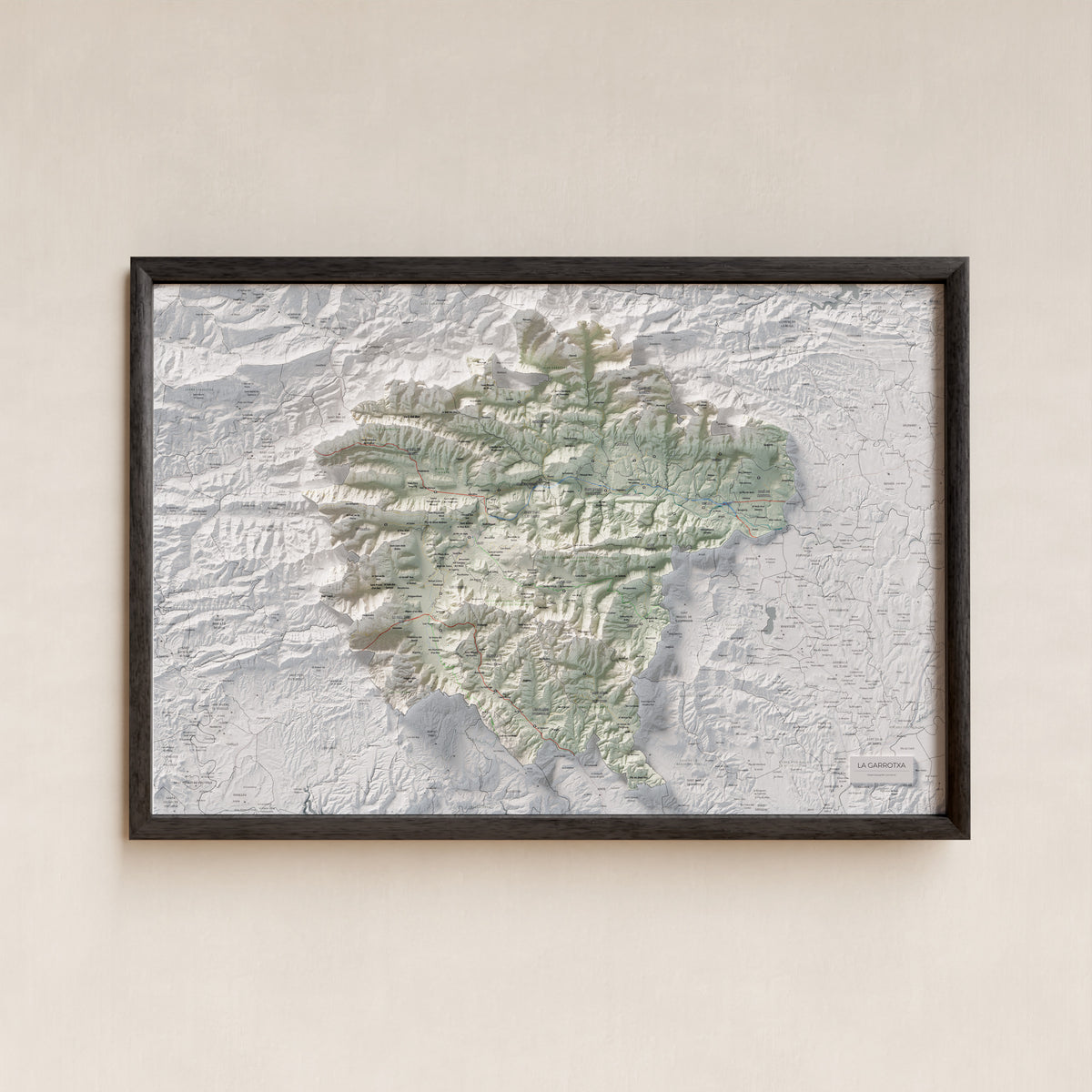 Mapa de relleu de la Garrotxa, amb el territori en color i l’entorn en blanc. Presentació amb marc. 61 × 91 cm. Estil Cartogràfic.