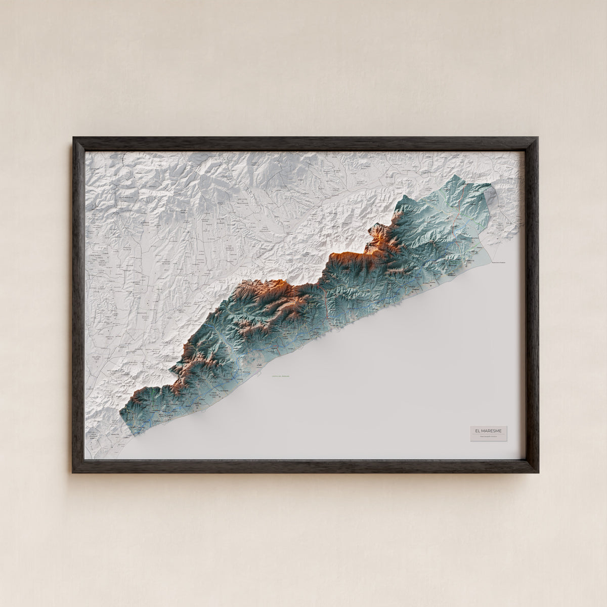 Mapa de relleu del Maresme, amb el territori en color i l’entorn en blanc. Presentació amb marc. 70 × 100 cm. Estil Blau i taronja.