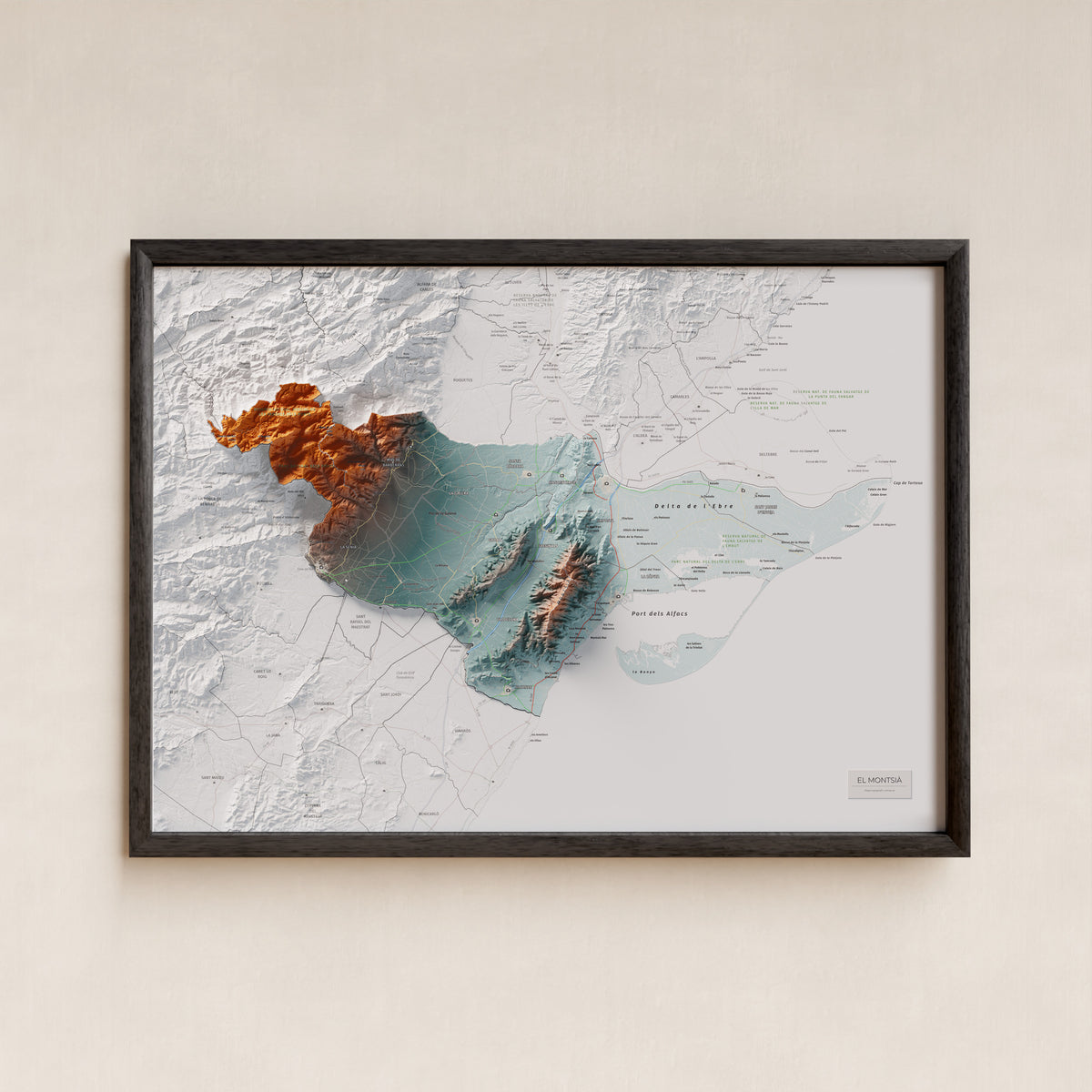 Mapa de relieve del Montsià, con el territorio en color y el entorno en blanco. Presentación con marco. 50 × 70 cm. Estilo Azul y naranja.
