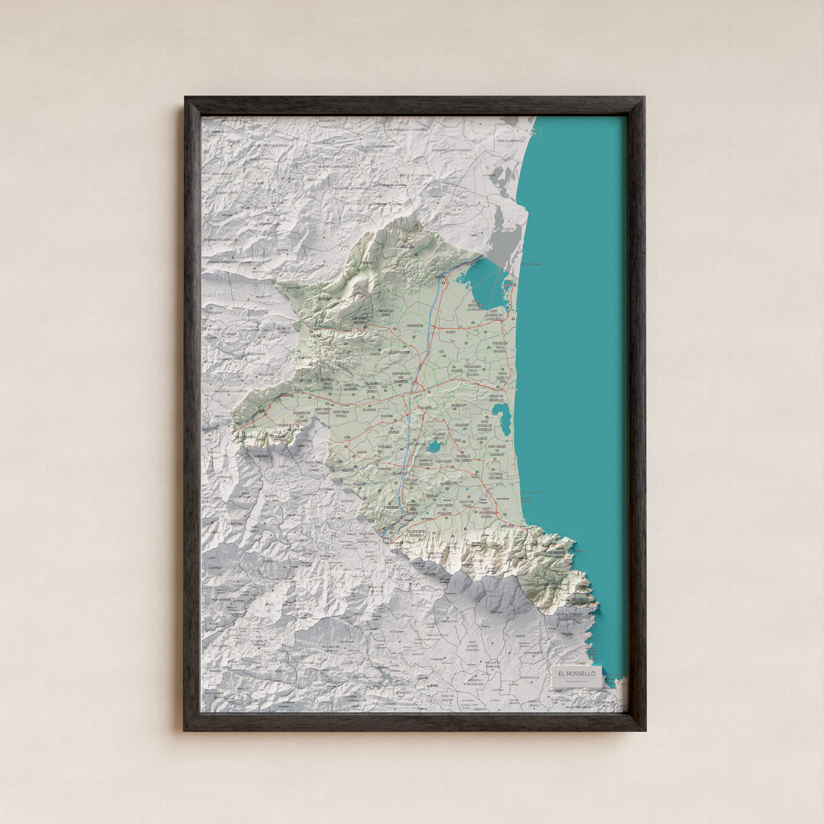 Mapa de relieve del Rosselló, con el territorio en color y el entorno en blanco. Presentación con marco. 50 × 70 cm. Estilo Cartográfico.