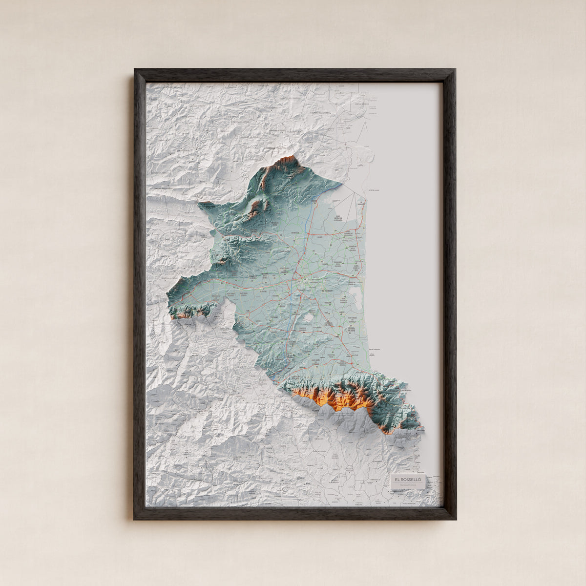 Mapa de relieve del Rosselló, con el territorio en color y el entorno en blanco. Presentación con marco. 70 × 100 cm. Estilo Azul y naranja.