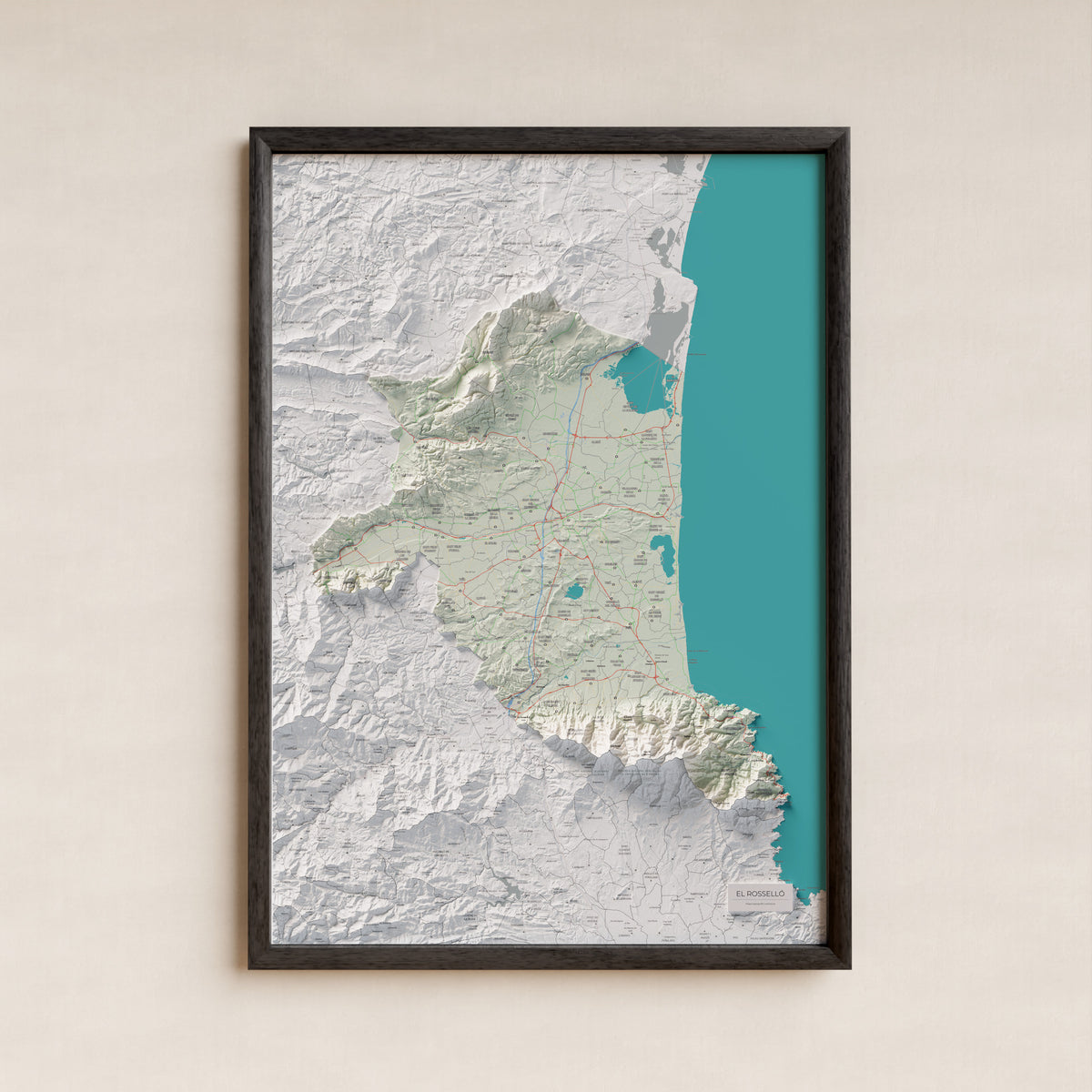 Mapa de relieve del Rosselló, con el territorio en color y el entorno en blanco. Presentación con marco. 70 × 100 cm. Estilo Cartográfico.